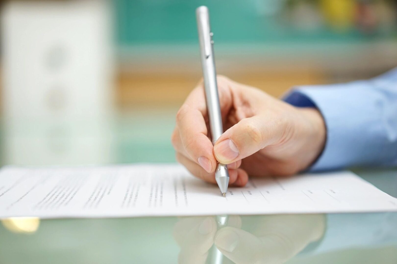 A person writing on paper with a pen.